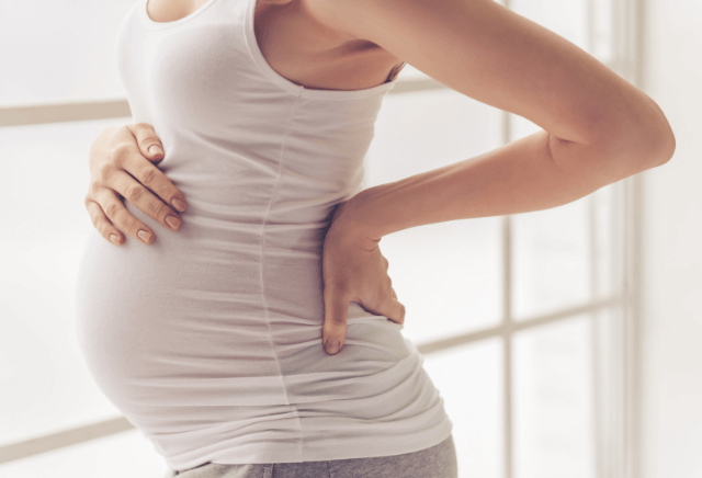 お腹と腰をおさえる妊娠中の女性